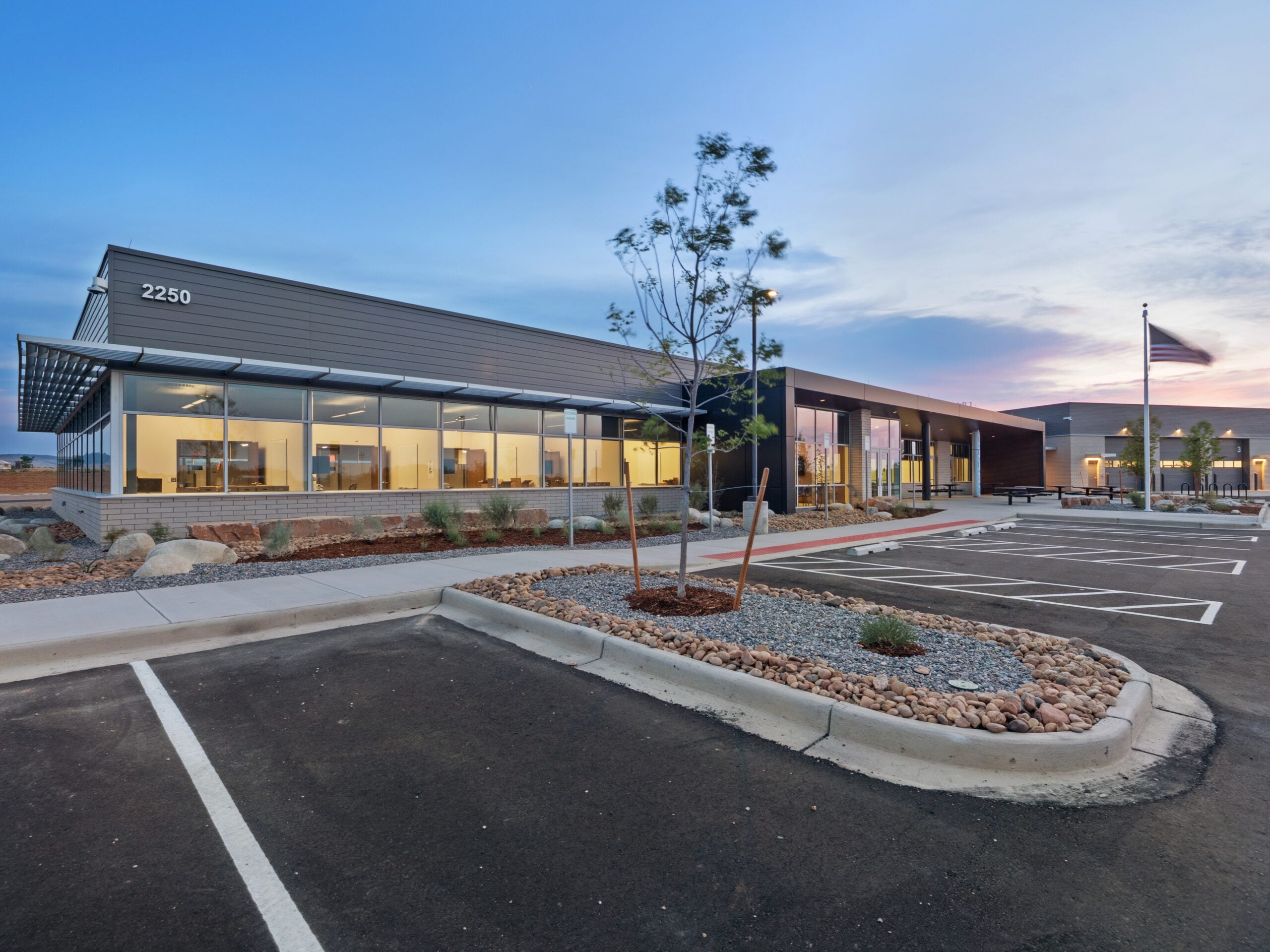 Exterior view at dusk of the Larimer County Emergency Services Building's administrative office entrance and landscaped parking area