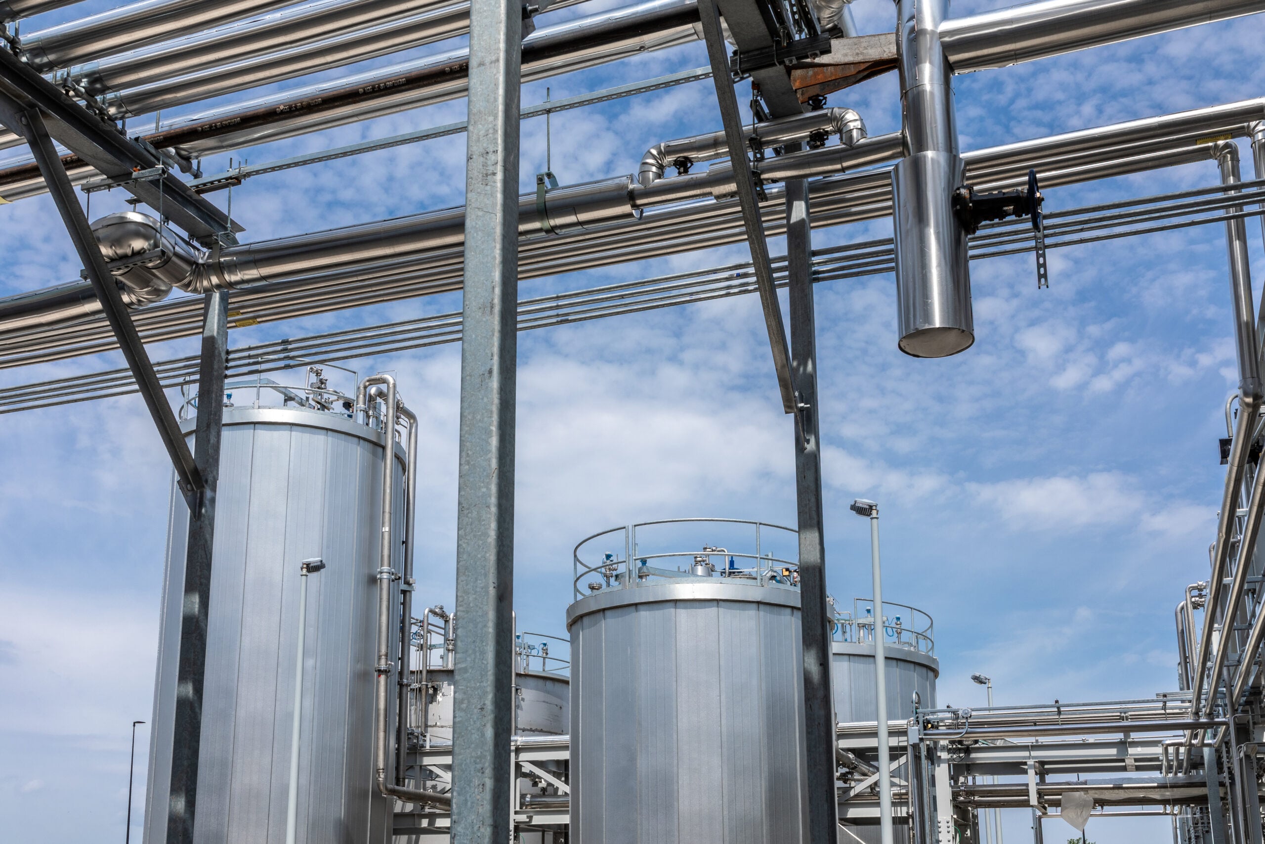 - JE Dunn Construction Exterior stainless steel storage tanks and overhead process piping at a battery electrolyte manufacturing plant"