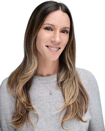 Smiling woman with long wavy hair wearing a light gray sweater, facing the camera.